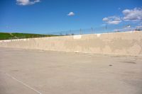 there is a white skateboard parked in a parking lot near the fenced area