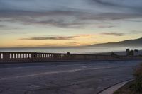 the coast with waves is at the right of this photo, a person riding his motorcycle on the street