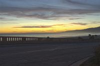 the coast with waves is at the right of this photo, a person riding his motorcycle on the street