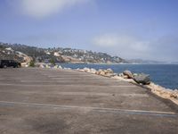 the car is parked in a parking lot near the ocean shore and is parked next to the cliff