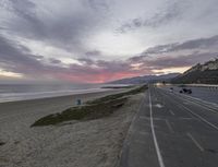 the view from the sidewalk shows a freeway next to the beach and ocean with no cars on it