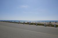 a paved area next to the ocean with a few posts sticking out of it on a clear, blue day