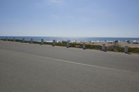 a paved area next to the ocean with a few posts sticking out of it on a clear, blue day