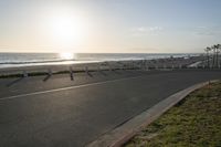 an empty road near a beach and waves as well as cars on the sand and houses on the beach