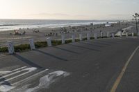 an empty road near a beach and waves as well as cars on the sand and houses on the beach