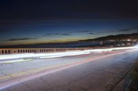 the coast with waves is at the right of this photo, a person riding his motorcycle on the street