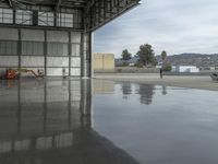 a large airplane parked inside an airplane hangar by itself on a wet surface with two men walking behind it