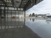 a large airplane parked inside an airplane hangar by itself on a wet surface with two men walking behind it