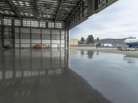 a large airplane parked inside an airplane hangar by itself on a wet surface with two men walking behind it