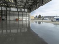 a large airplane parked inside an airplane hangar by itself on a wet surface with two men walking behind it