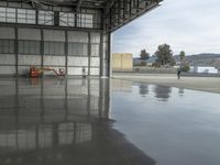 a large airplane parked inside an airplane hangar by itself on a wet surface with two men walking behind it