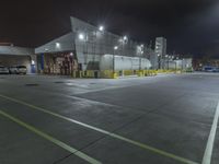 a factory with tanks at night time, in the background an industrial building with metal poles and overhead lighting