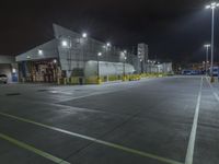 a factory with tanks at night time, in the background an industrial building with metal poles and overhead lighting