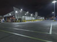 a factory with tanks at night time, in the background an industrial building with metal poles and overhead lighting