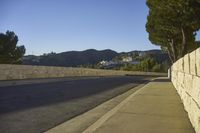 a concrete bridge next to the side of a road that is beside a hill with trees