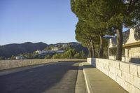 a concrete bridge next to the side of a road that is beside a hill with trees