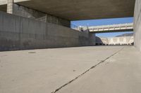 a road has concrete overpass and cement wall with cement under bridge area in background