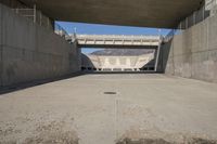 a road has concrete overpass and cement wall with cement under bridge area in background