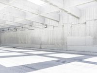 a empty warehouse with light coming from the roof and a shadow cast on the floor