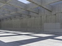 a empty warehouse with light coming from the roof and a shadow cast on the floor