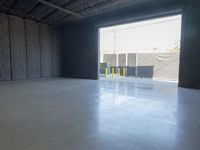 a gray concrete floor with a light from the inside is visible in this empty building