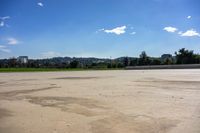 a lone skateboard is in a concrete parking lot with trees in the background and blue skies