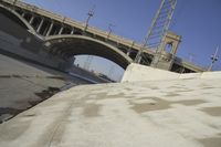 a skate board is standing on the road under a bridge overpass with power lines