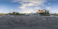 a 360 - angle view of a parking lot at sunset showing some buildings and a car park