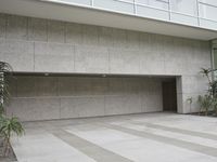 a white concrete structure outside an office building with windows and plants growing on the stone tiles