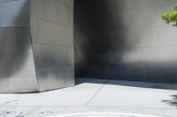 a red fire hydrant is on a large walkway near a building made of shiny metallic