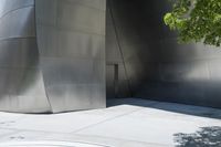 a red fire hydrant is on a large walkway near a building made of shiny metallic