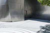 a red fire hydrant is on a large walkway near a building made of shiny metallic