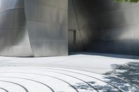 a red fire hydrant is on a large walkway near a building made of shiny metallic