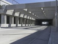 an empty street and some light beams on the top of it, and there is a stop sign with red letters