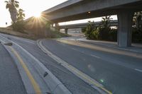 the sun is going down over a highway with palm trees in front of it and several ramps on either side