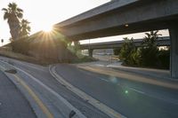 the sun is going down over a highway with palm trees in front of it and several ramps on either side