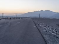 a street that has a lot of rocks on it with the sun setting in the background