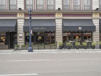 a building with awnings and tables in front of it on the street corner