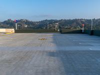 a empty parking lot is shown with hills and a hill in the background during a sunny day