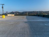 a empty parking lot is shown with hills and a hill in the background during a sunny day