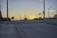 a bridge with a ramp and several street lights lit by the setting sun on the road