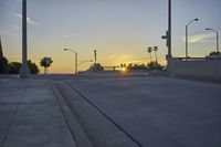 a bridge with a ramp and several street lights lit by the setting sun on the road