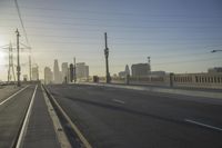 an empty highway with power lines leading to city buildings in the back ground and road tracks