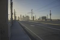 an empty highway with power lines leading to city buildings in the back ground and road tracks