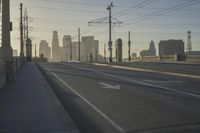 an empty highway with power lines leading to city buildings in the back ground and road tracks