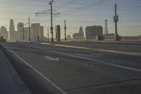 an empty highway with power lines leading to city buildings in the back ground and road tracks