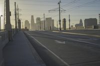 an empty highway with power lines leading to city buildings in the back ground and road tracks