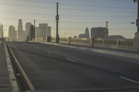 an empty highway with power lines leading to city buildings in the back ground and road tracks