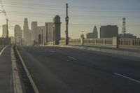 an empty highway with power lines leading to city buildings in the back ground and road tracks