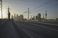 an empty highway with power lines leading to city buildings in the back ground and road tracks